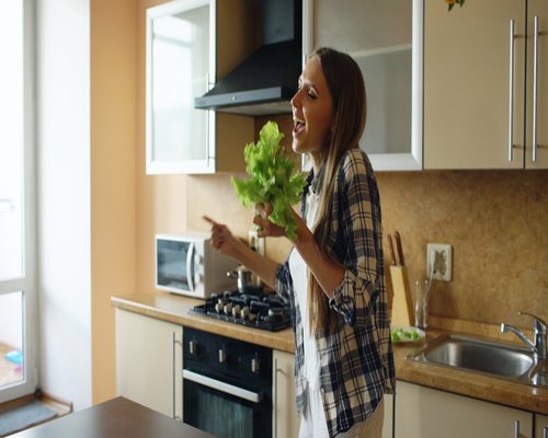Smiling woman preparing fresh salad in a bright kitchen
